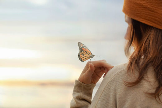 Frau-am-Stand-Schmetterlin Frau am Strand mit Schmetterling auf der Hand